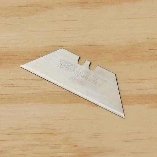 STANLEY 11-921 utility knife blade, silver, single blade shown on wood background, angled top view.