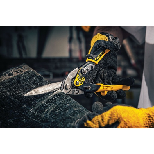 STANLEY 14-566 aviation snips with yellow and black handle cutting sheet metal, photographed in a workshop setting.