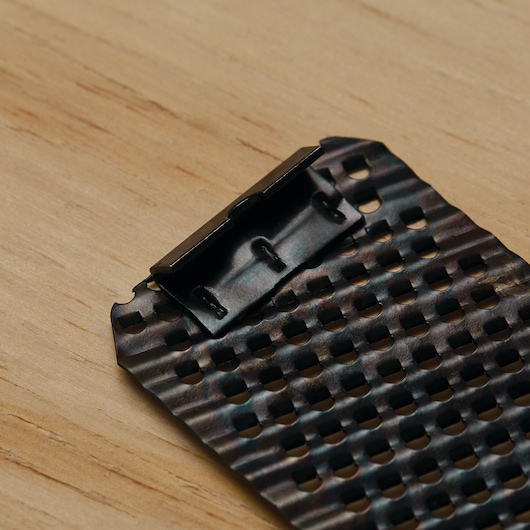 Photo of STANLEY 21-398 replacement surform blade with perforated metal surface, close-up angle on wood background.