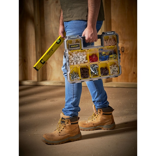 STANLEY FMST14820 organizer case with yellow compartments, carried by a person holding a STANLEY level tool.