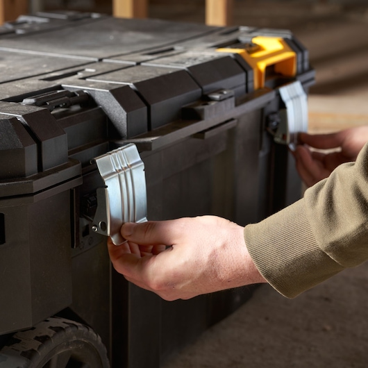 Photo of STANLEY FMST17870-1 black tool box with metal latches being secured, close-up side view.