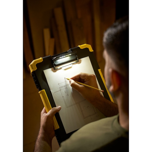 STANLEY FMST82721-1 clipboard with LED light, shown from above in use, holding a pencil and drawing plans.