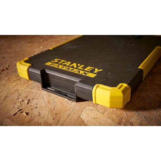 Stanley FMST82721-1 tool case with yellow reinforced corners, photography close-up on wood surface.