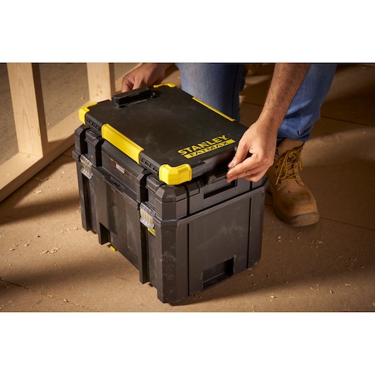 Photo of STANLEY FMST82721-1 black and yellow tool storage box being latched, jobsite setting.