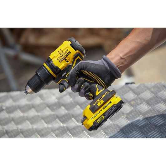 STANLEY SBD710D2KA yellow cordless drill held by gloved hand, side angle, photography product category.
