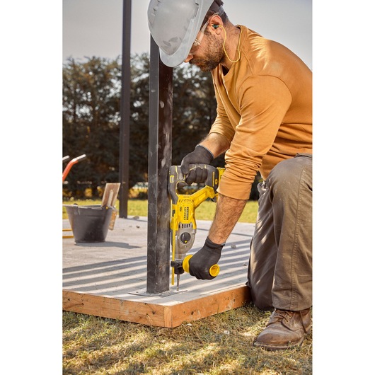 STANLEY SBH900 rotary hammer drill used on metal post at construction site, outdoor setting.