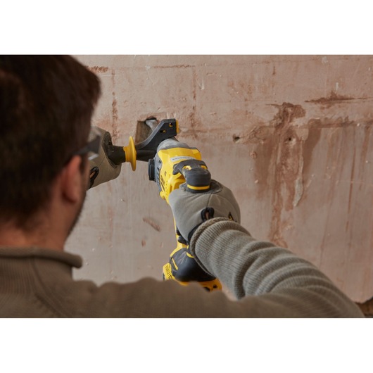 STANLEY SBH900 rotary hammer drill in use against a wall, close-up photo showing gloved hands.