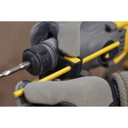 Photo of STANLEY SBH900 drill with yellow depth gauge, gloved hands adjusting tool, close-up angle.