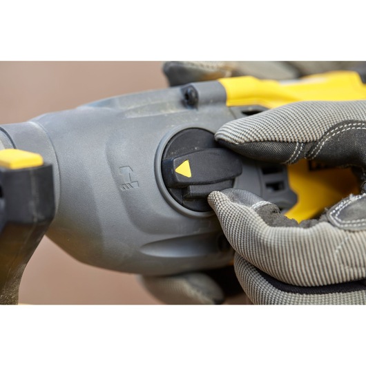 STANLEY SBH900 rotary hammer close-up, gloved hand adjusting mode selector switch.