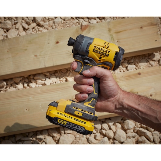 Photo of STANLEY SKU SBI810D2K-B3 cordless impact driver, yellow and black, handheld on construction site.