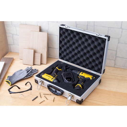 STANLEY SCHI10 power tool kit with black foam case, gloves, safety glasses and screws on wooden table.