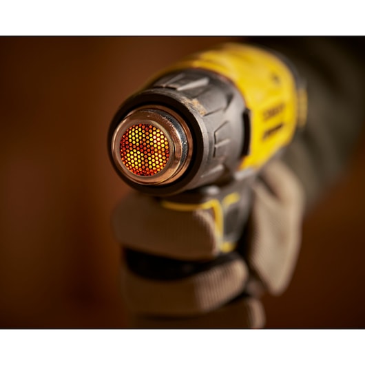STANLEY SCX530B-B3 heat gun close-up, yellow and black body, glowing nozzle, in gloved hand.