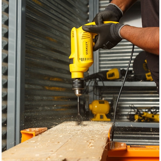 Stanley SDH600KP corded drill in use drilling wood, close-up side angle, photography product category.
