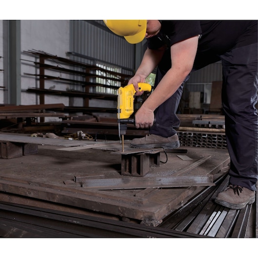 STANLEY SDH600K hammer drill used on metal sheet in workshop by worker wearing yellow helmet.