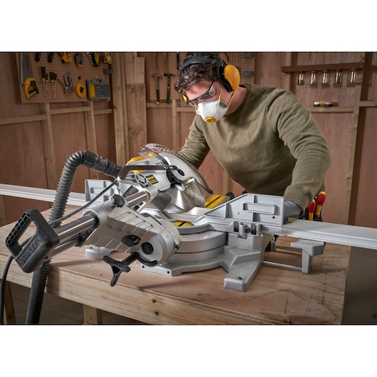 STANLEY SM181 sliding compound miter saw on workbench shown in use cutting wood in a workshop.