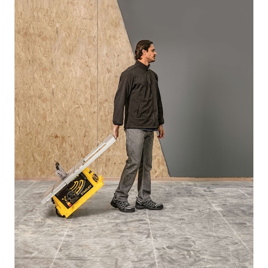 STANLEY SST1801-B3 portable table saw being wheeled by a person, photo in workshop setting.