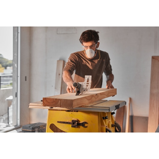 STANLEY SST2001-B2 table saw in use cutting a wooden board in a workshop, side angle view.