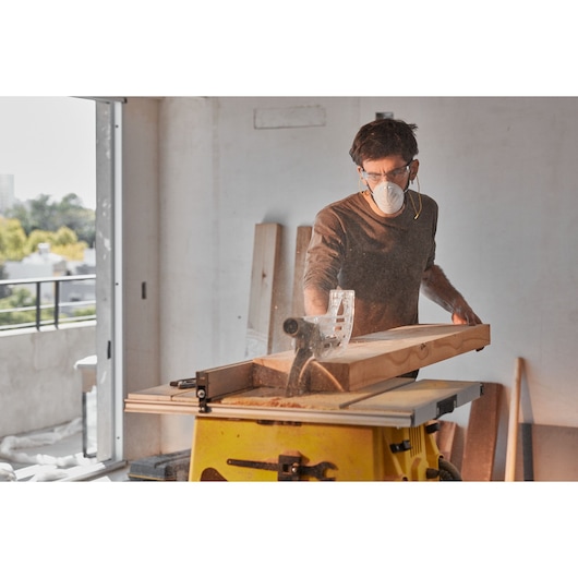 STANLEY SST2001-B2 table saw in use, cutting a wooden board indoors, side angle.