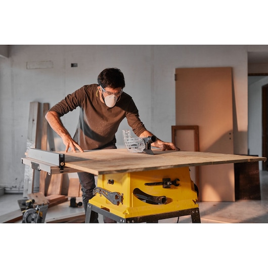 STANLEY SST2001-B2 table saw in workshop with woodworker cutting large plywood sheet.