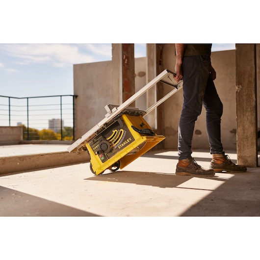 STANLEY SST2001-B2 portable table saw being wheeled by a person at a construction site.
