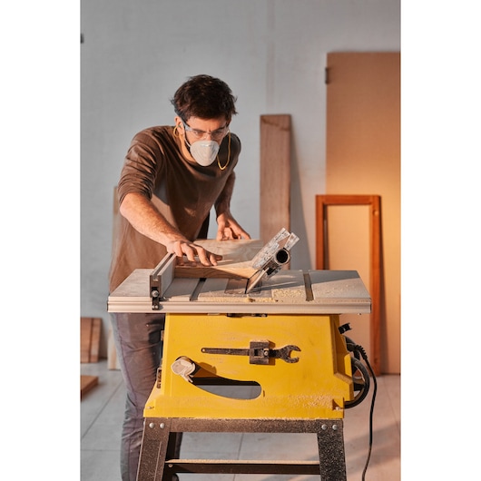 Photo of STANLEY SST2001-B2 table saw in use, yellow base, wood being cut in a workshop setting.