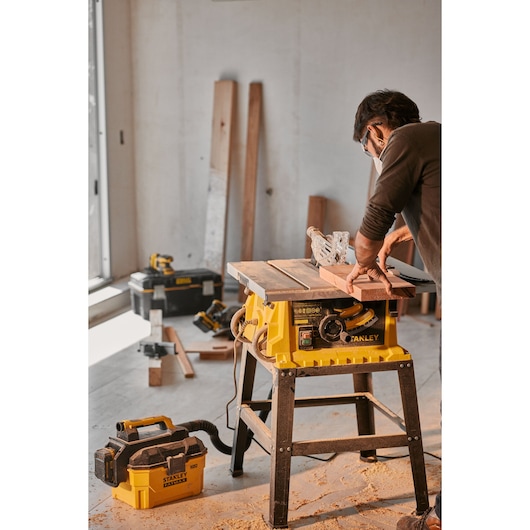 Stanley SST2001-B2 table saw in use, yellow body, woodworking setup, indoor workshop, side angle.