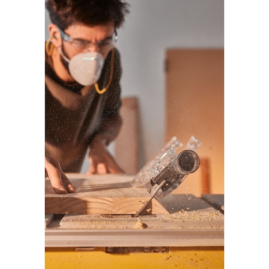 STANLEY SST2001-B2 table saw close-up cutting wood, sawdust flying, person operating, workshop setting.