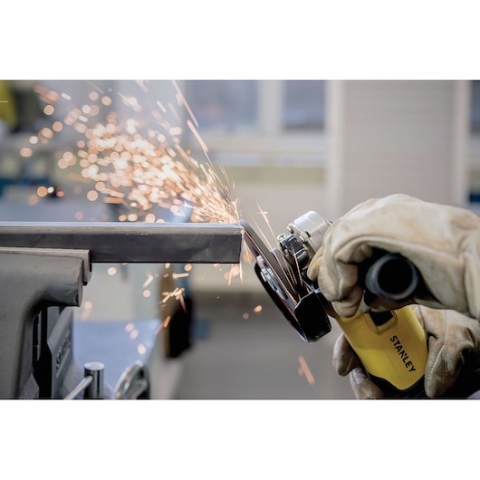 STANLEY STA0413 angle grinder in use, grinding metal with sparks flying, close-up photography.