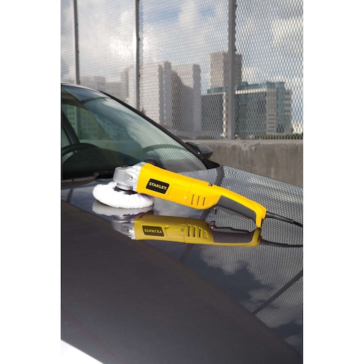 STANLEY STGP612K car polisher with yellow and black handle in use on a car hood, outdoor setting.