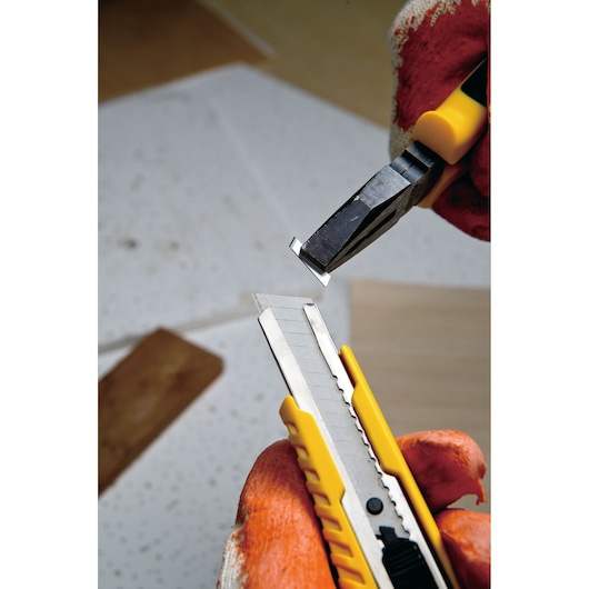 STANLEY STHT10276-8 utility knife with segmented blade, gloved hand snapping off blade section, close-up angle.