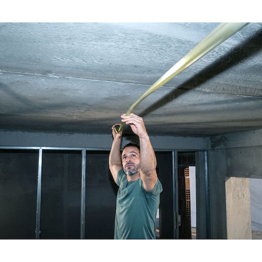 Man using STANLEY STHT37246-0 tape measure on ceiling in construction area.