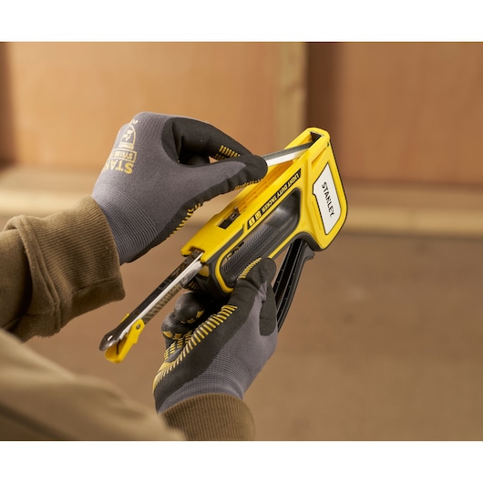 Photo of STANLEY STHT70440 heavy-duty stapler in use, worker wearing gloves loading staples.