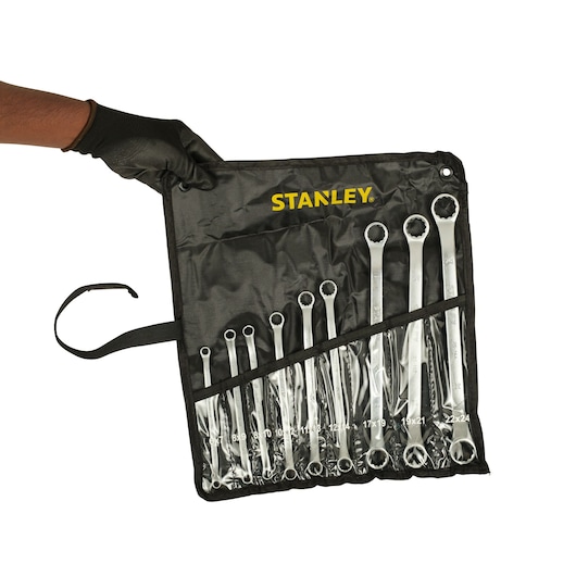 Photo of STANLEY STMT25147 set of combination wrenches in black roll-up pouch, held by gloved hand, front angle.