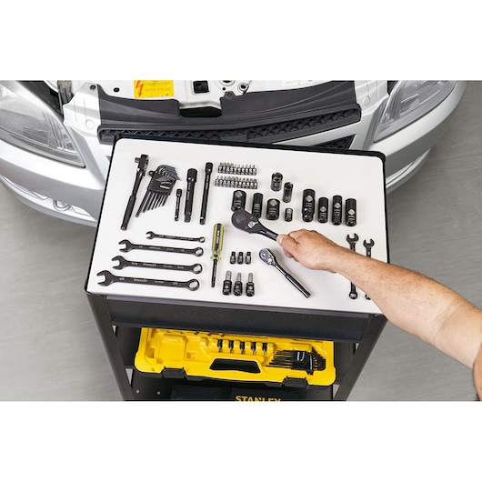 STANLEY STMT71662-LA automotive tool set with wrenches, sockets, and ratchets on workbench, top view.