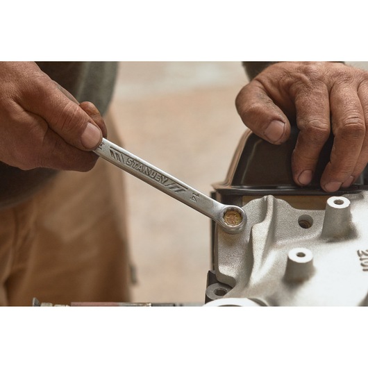 Photo of STANLEY STMT72811 wrench in use tightening bolt on machinery with hands visible.