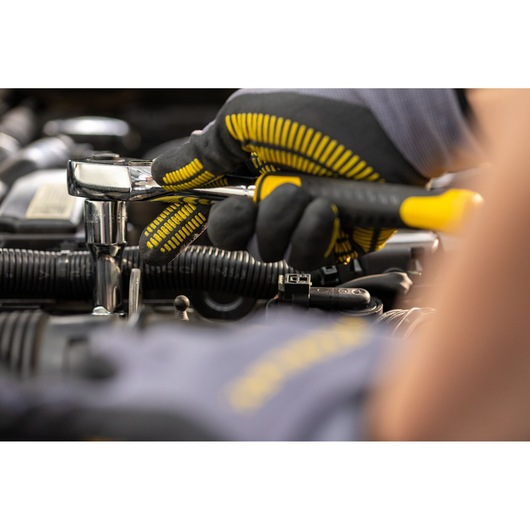STANLEY STMT82830-LA ratchet wrench used by gloved hand for automotive repair, close-up.