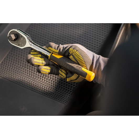 Photo of a gloved hand holding a STANLEY STMT82830-LA ratchet wrench with yellow and black handle.