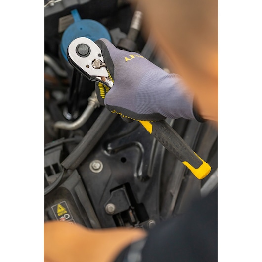 Photo of STANLEY STMT82832-LA ratchet wrench with black and yellow handle in use on machinery.