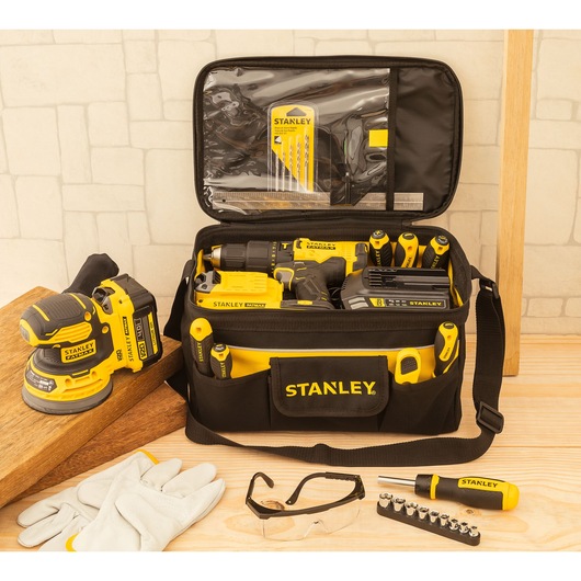 STANLEY STST1-73615 tool kit bag with yellow and black hand tools and accessories on wood table, frontal view.