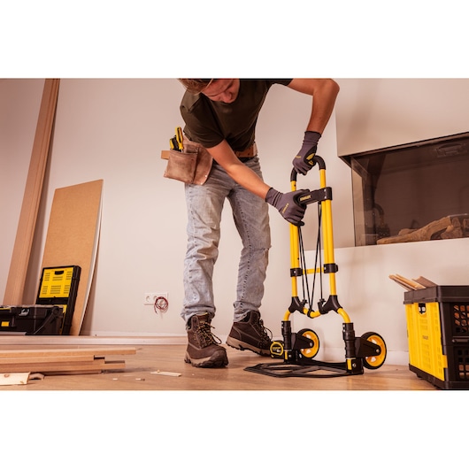 Stanley STST98022L yellow foldable hand truck in use during home renovation, side angle.