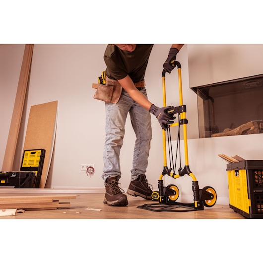 STANLEY STST98022L folding hand truck, yellow-black, construction site setting, photography of side angle.